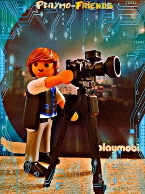 Playmobil-Figur mit Kamera auf einem Stativ